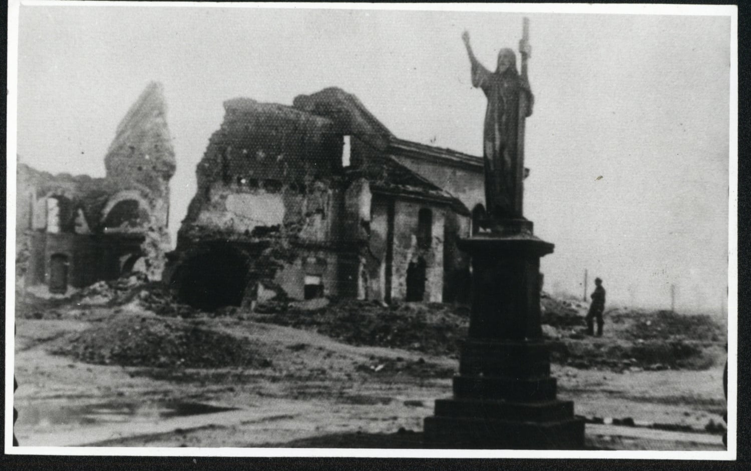 czarno-biełą zdjęcie przedstawia figurę Chrystusa na&nbsp;tle zniszczonych budynk&oacute;w